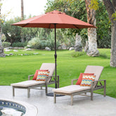 Two lounge chairs and a large umbrella set on a patio, providing a shaded area for relaxation.